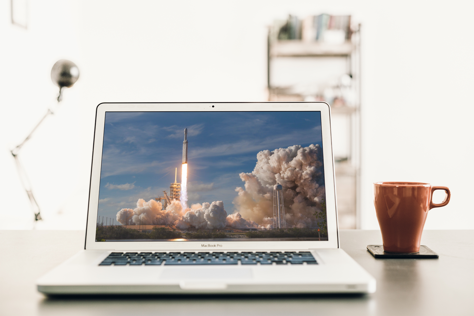 An open laptop sits to the left of a coffee cup.