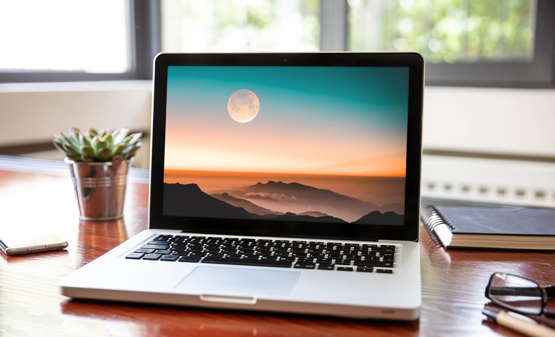 A Macbook sits open on a home office desk. 